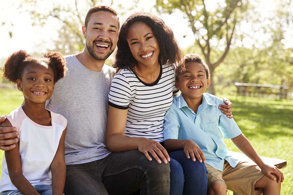 outdoor portrait of smiling family sitting on benc 2021 08 26 16 15 07 utc